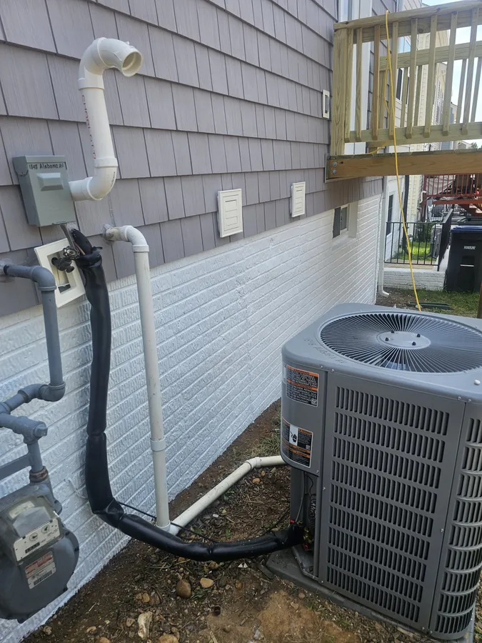 Outdoor condensing unit installed beside a house with new line set and disconnect box